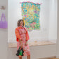 Person standing in front of a colorful abstract painting in an art gallery.