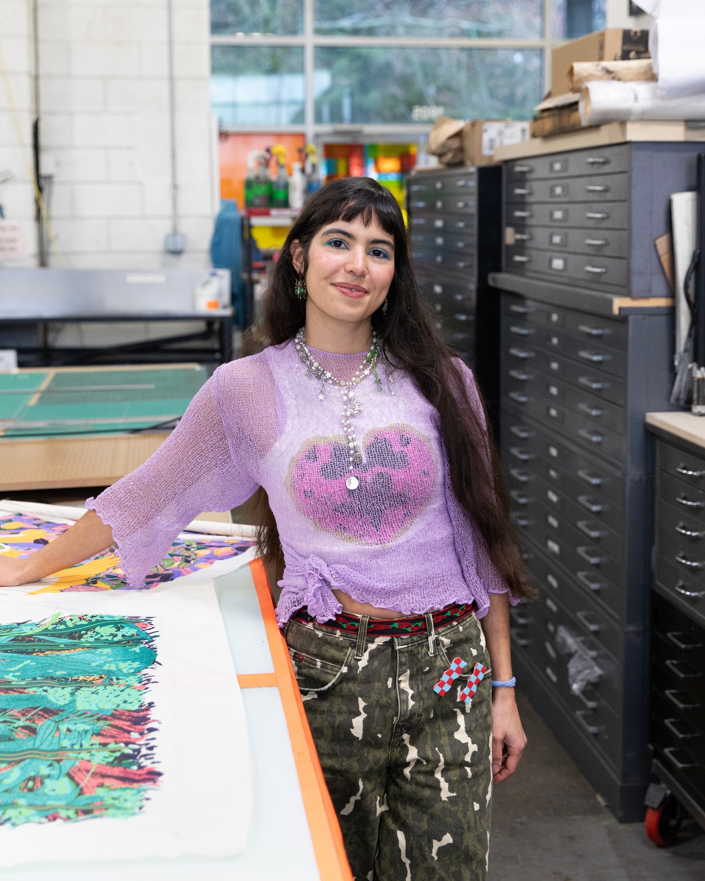 Person wearing a purple shirt with a graphic design in an art studio setting